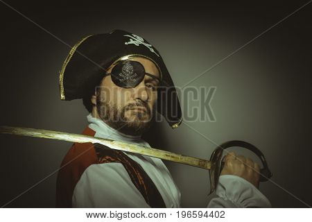 Man with beard dressed like a pirate, with eye patch and steel sword