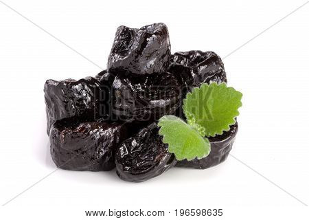 heap of dried plums or prunes with a mint leaf isolated on white background.