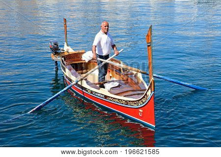 VITTORIOSA, MALTA - MARCH 31, 2017 - Man steering a traditional Maltese Dghajsa water taxi in the harbour Vittoriosa Malta Europe, March 31, 2017.