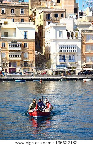 VITTORIOSA, MALTA - MARCH 31, 2017 - Passengers on board a traditional Maltese Dghajsa water taxi in the harbour with views towards Senglea waterfront Vittoriosa Malta Europe, March 31, 2017.