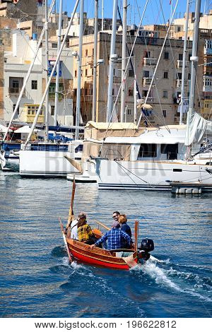 VITTORIOSA, MALTA - MARCH 31, 2017 - Passengers on board a traditional Maltese Dghajsa water taxi in the harbour with views towards Senglea waterfront Vittoriosa Malta Europe, March 31, 2017.
