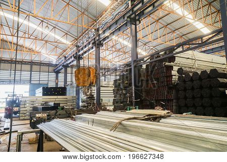 lifting crane with yellow hook in steel pipe warehouse