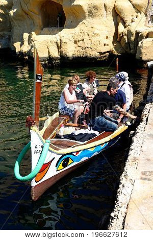 VITTORIOSA, MALTA - MARCH 31, 2017 - Passengers on board a traditional Maltese Dghajsa water taxi in an inlet alongside Fort San Angelo Vittoriosa Malta Europe, March 31, 2017.