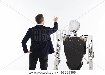 High tech computer. Ambitious capable hardworking man using special interactive projection on the wall for adjusting specific setting for his robot