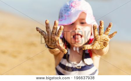 Little girl showing her hands with sand on the palms