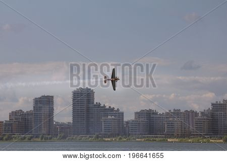 Small sport aircraft flying over modern city, telephoto