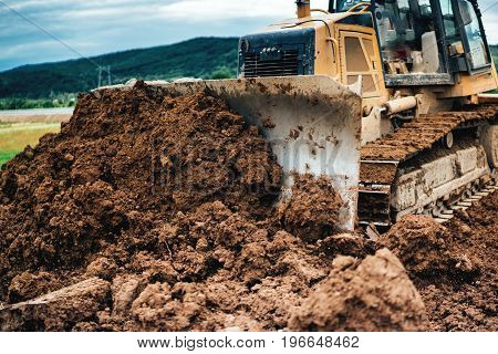 Yellow Mini Bulldozer Working With Earth And Soil While Doing Landscaping Works On Construction Site