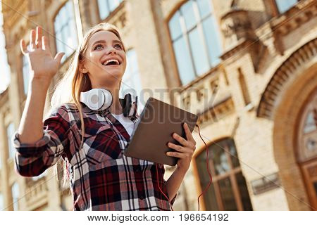 Come here, guys. Sincere pretty easy going woman waving her hand and greeting her fellow students who also heading to the class today