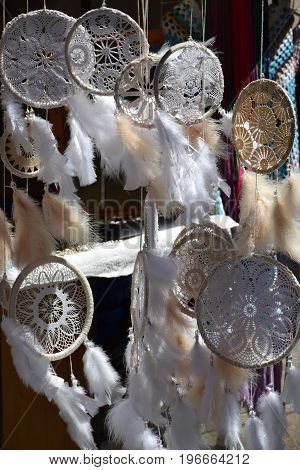 Dream Catchers, made of white lace and feathers, swing in the wind