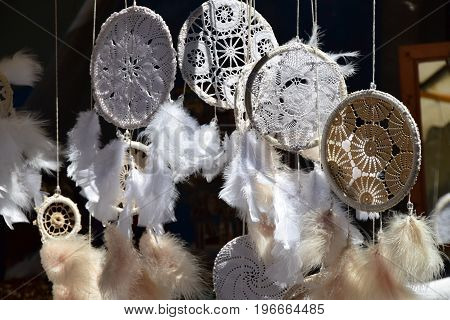 Dream Catchers, made of white lace and feathers, swing in the wind