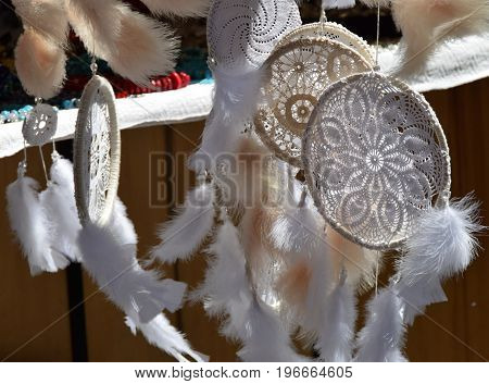 Dream Catchers, made of white lace and feathers, swing in the wind