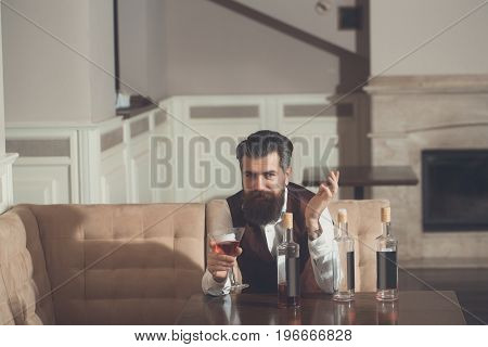 Man Sitting On Sofa With Martini Glass And Three Bottles