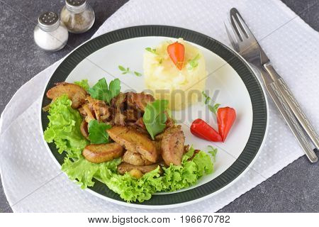 Fried bull testicles with cream and herbs served with mashed potato on a white plate on an abstract background. Healthy food concept