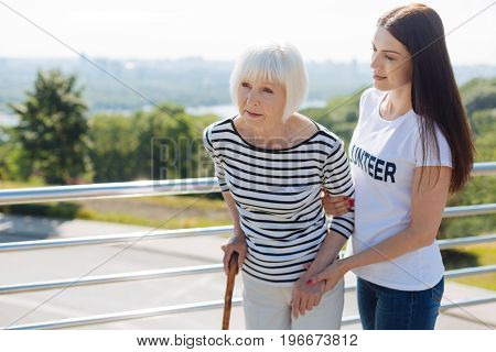 I will escort you. Graceful admirable sincere woman helping elderly people living their lives normally while helping them on a daily basis