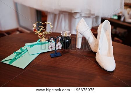 Bridal Perfume, White High Heels, Chic Earrings And Wedding Atributes Laying On The Table.