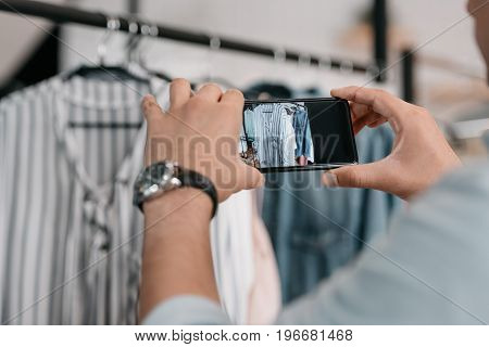 Close-up Partial View Of Young Man Photographing Clothes With Smartphone