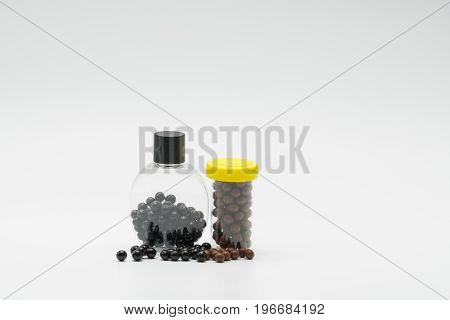 Thai herbal medicine in plastic bottle with modern design and many pills spread on a white background bolus