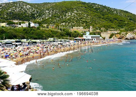 SITGES, SPAIN - JULY 9, 2017: People enjoying, relaxing, sunbathing or bathing at the Garraf Beach in Sitges, a popular beach in the coast of the Metropolitan Area of Barcelona, in Catalonia