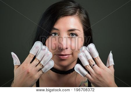 Portrait of young woman wearing nails protector in her nails, hand and ideal clean manicure, in a black background.