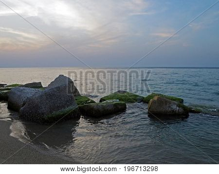 Moss Covered Rock In The Sea With The Sunset Sky