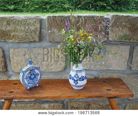 Demotic  White Blue Painted Pottery Flask And Vase With Field Flowers Ond Sandstone Wall Background