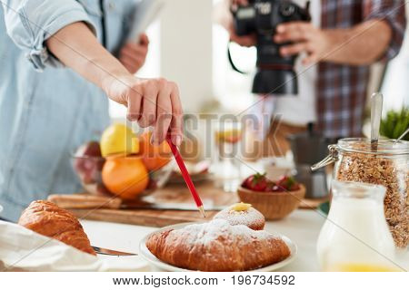 Food-stylist pointing at fresh croissant during working process