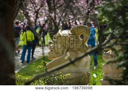 Korean tradition stone idol in the flowered spring park. A view through the trees.