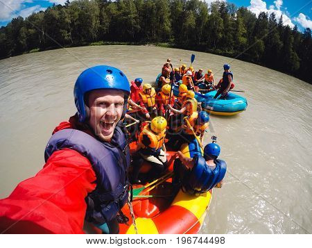 mountain Altai, biryuzovaya katun, RUSSIA - July 16, 2017: man in a helmet holds an action camera and makes selfie on the background of friends with oars, rafting