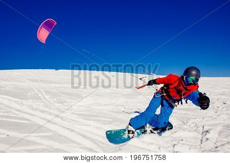 Snowboarder with a kite on fresh snow in the winter in the tundra of Russia against a clear blue sky. Teriberka, Kola Peninsula, Russia. Concept of winter sports snowkite.