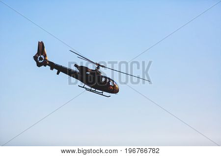 A flying black helicopter aircraft during the flight with blue sky in the background