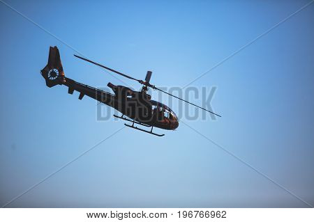 A flying black helicopter aircraft during the flight with blue sky in the background
