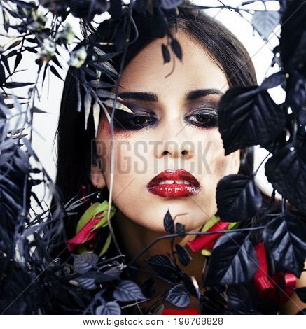 pretty brunette woman with rose jewelry, black and red, bright make up kike a vampire closeup red lips, halloween concept