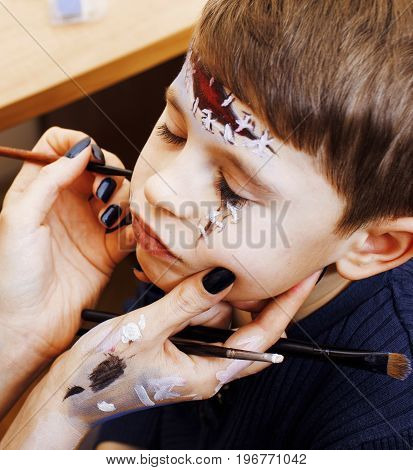 little cute child making facepaint on birthday party, zombie Apocalypse facepainting, halloween preparing concept, lifestyle people close up
