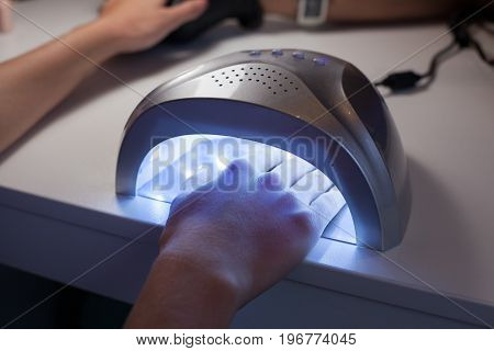 Girl dries nail Polish in a UV lamp in a beauty salon.