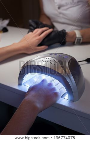 Girl dries nail Polish in a UV lamp in a beauty salon.