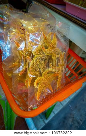 Dry sea stars inside of a plastic bags, in an orange baskets, in a market in fishermen town in lantau, Hong Kong, China.