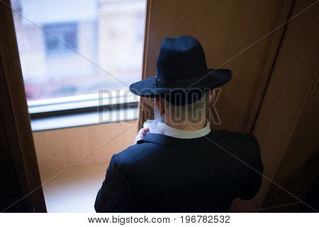 Jew Hasid Ethnic Headdress. The Jew Prays Before The Window. View From Above