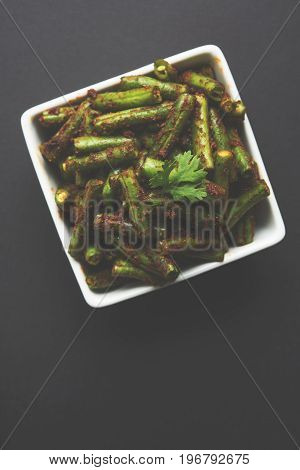 A Masala or fried vegetable dish consisting of green beans, onions, and curry spices, served in square bowl, selective focus