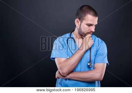 Portrait Of Doctor Wearing Scrubs With Stethoscope Thinking