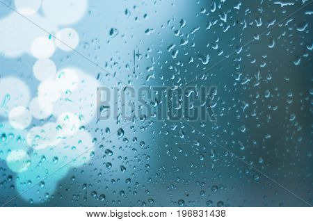 drops of rain on window glass with lights bokeh