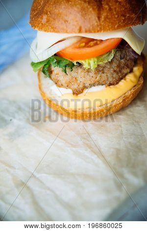 hamburger: tomato, cheese, chicken, onion, greens, on a blue wooden background. place under your account, text