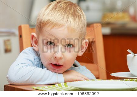 Morning routine in family healthy diet for children concept. Bored boy waiting for breakfast sitting in ktichen table