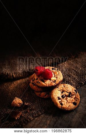 Chocolate chips cookies with berries macro on dark background with copy space