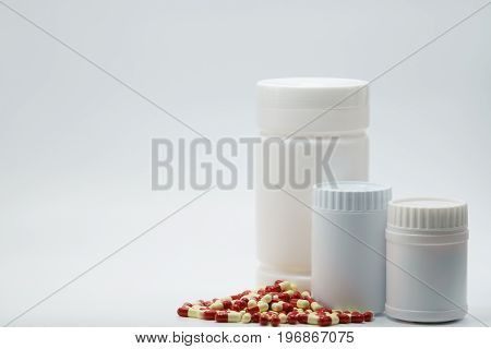 Antibiotic capsules with closed bottles on white background