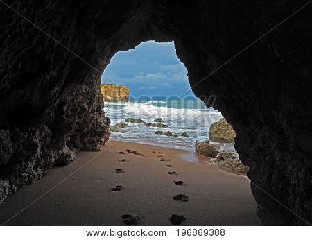 window view on footprints on a sandy beach leading to the blue sea