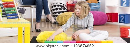 Young girl on psychotherapy playing with colorful blocks