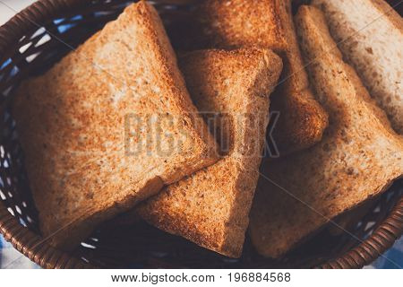 Breakfast background, white bread toasts in wicker breadbasket on checkered table napkin, closeup