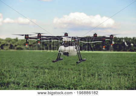Professional large drone spray water over a green field. Agriculture industry concept drone with flying green field.