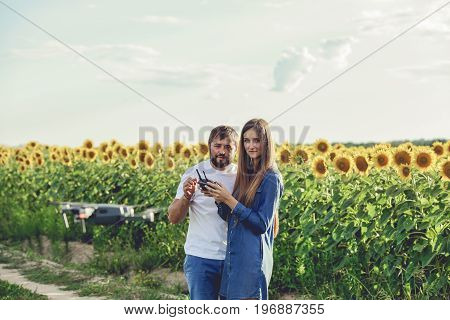 Young man operating of flying drone octocopter at the green field. Professional agriculture drone flying with blue sky.