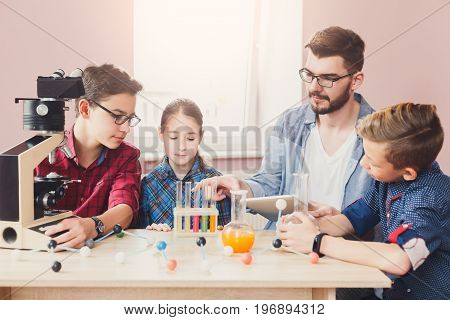 Stem education. Teenagers with teacher making chemical experiment in laboratory with reagents and microscope. Early development concept
